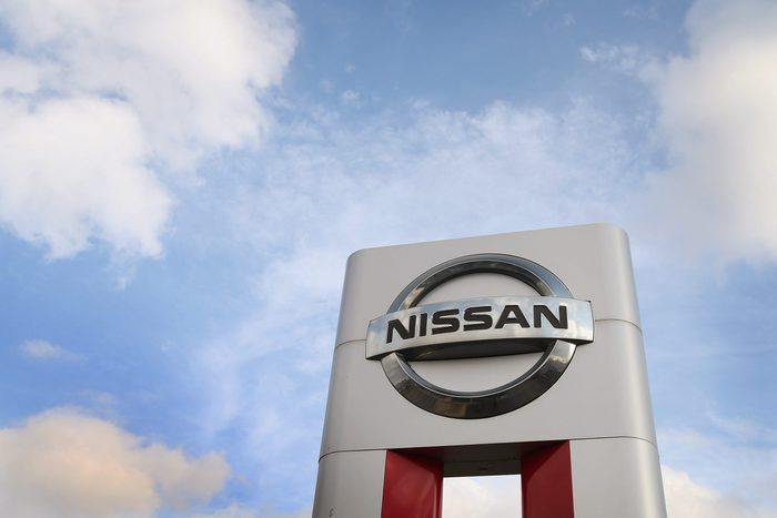Nissan Motor Company Sign Towers Above Dealership on a Blue Sky and Clouds