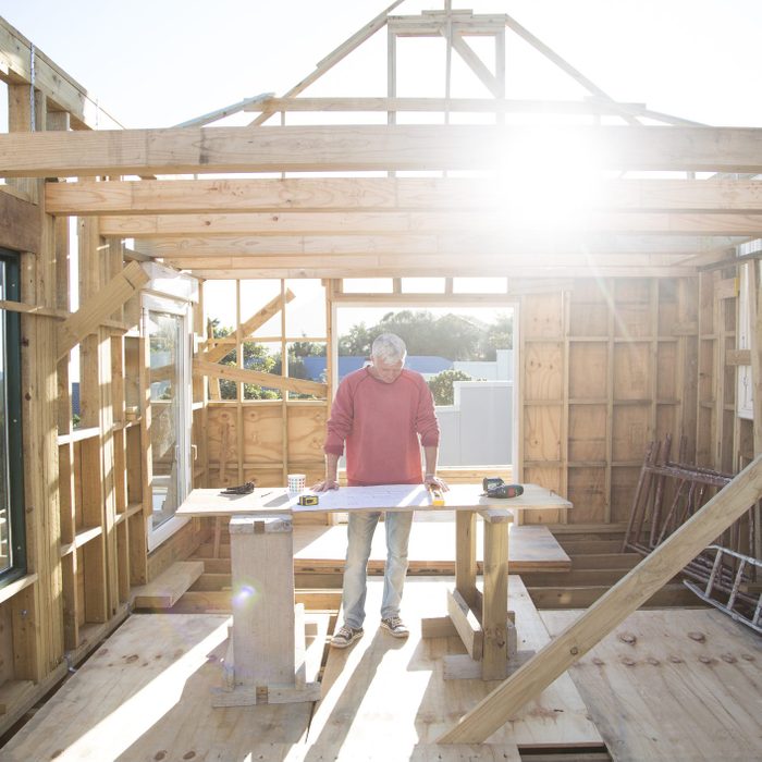 man looking at plans for house that is being built