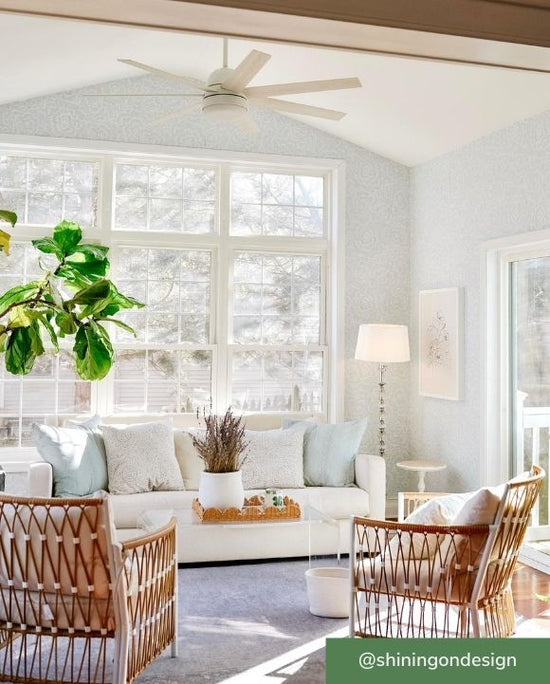 Aerodyne ceiling fan in white finish mounted with downrod on white ceiling of sunroom.